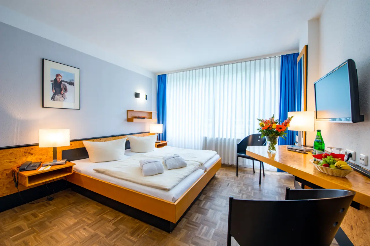 Gemütliches Doppelzimmer mit Holzboden, Schreibtisch und Bademänteln im Hotel an der Therme Bad Sulza.