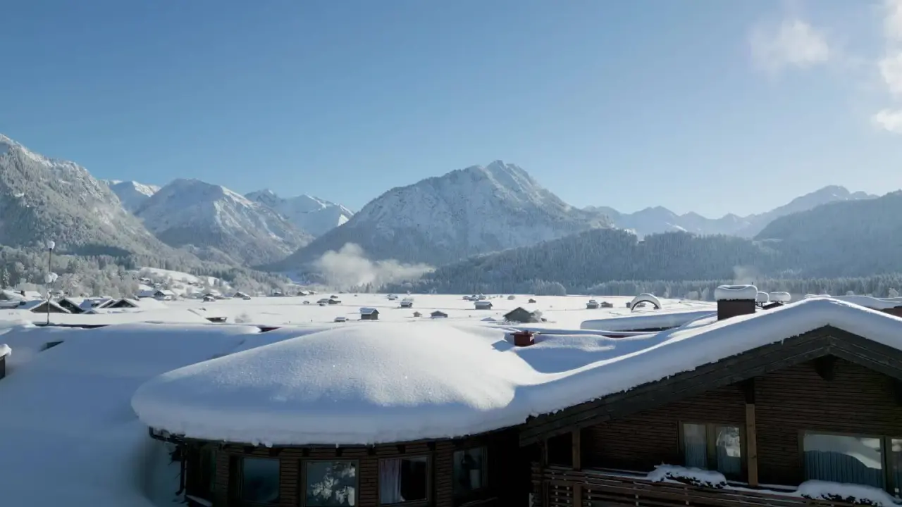 Winterlandschaft mit schneebedeckten Bergen und Dächern im SCHÜLE'S Gesundheitsresort & Spa.