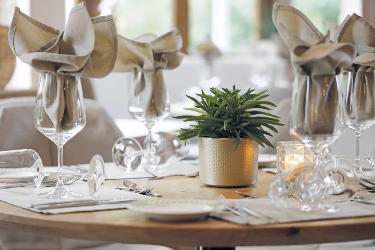Elegant gedeckter Tisch mit Pflanzen-Deko und Kerzenlicht im Restaurant des Hotel Grüner Wald****S.