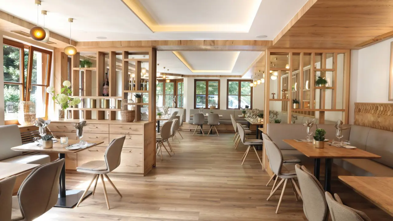 Modernes Restaurant im Hotel Grüner Wald****S mit Holzelementen, großen Fenstern und gemütlichen Sitzbereichen.