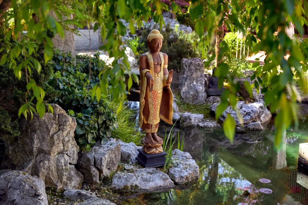 Buddha-Statue am Teich im ruhigen Garten des Ayurveda Resort Mandira, ideal zur Entspannung.