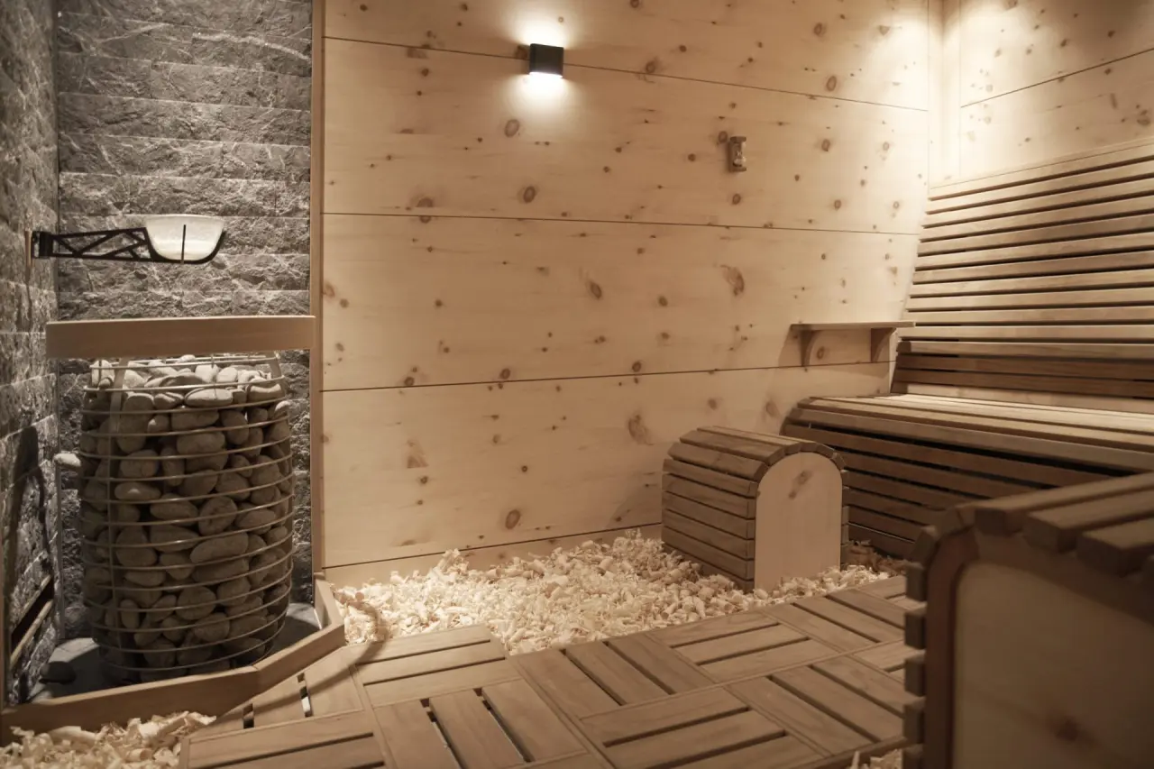 Moderne Finnische Sauna mit Natursteinwand, Holzvertäfelung und Salzschale im Wellnessbereich des Hotel Heinz.