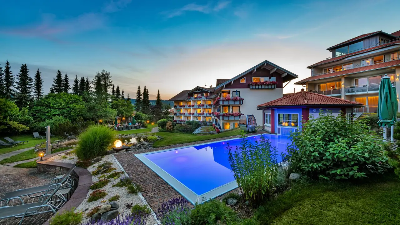 Abendliche Aussenansicht des Hotel Dein Engel mit leuchtendem Aussenpool und idyllischem Gartenbereich.