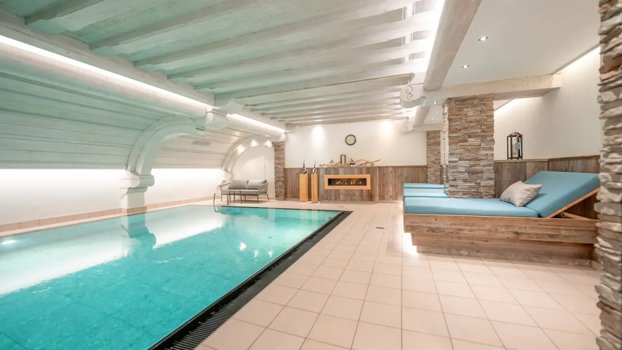 Gemütlicher Innenpool im Hotel Dein Engel mit Holzdecke, Kamin und bequemen Liegen für entspannte Wellnessmomente.