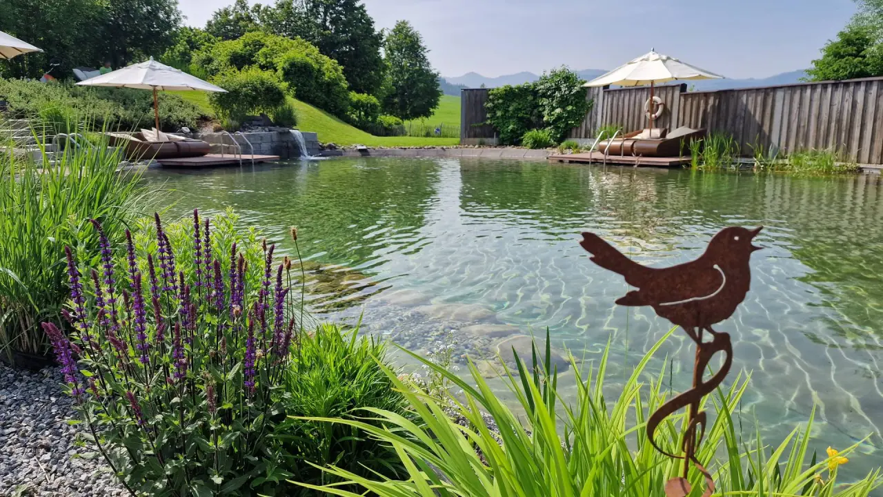 Naturschwimmteich mit Liegebereichen und Wasserfall im Wellnessbereich des Hotel Dein Engel.