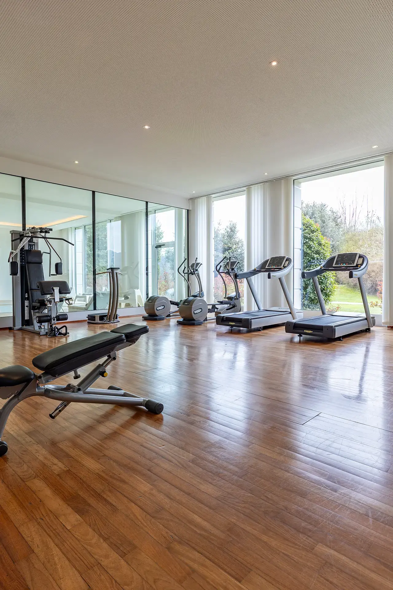 Moderner Fitnessbereich mit Laufbändern, Crosstrainern und Kraftgeräten im Resort Collina d'oro.
