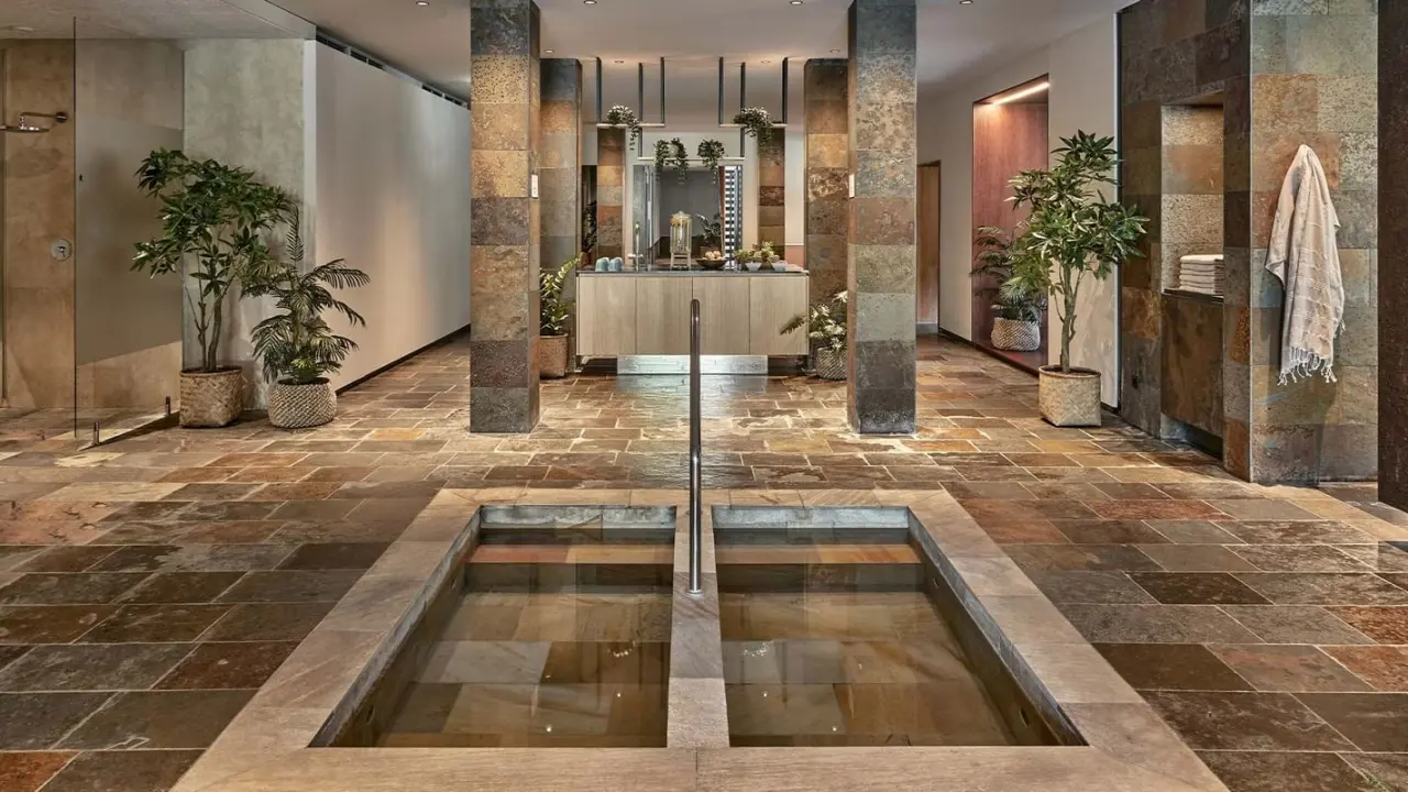 Kneipp-Becken und Erfrischungsbereich im modernen Spa des Falkensteiner Hotel Carinzia mit Naturstein und Pflanzen.