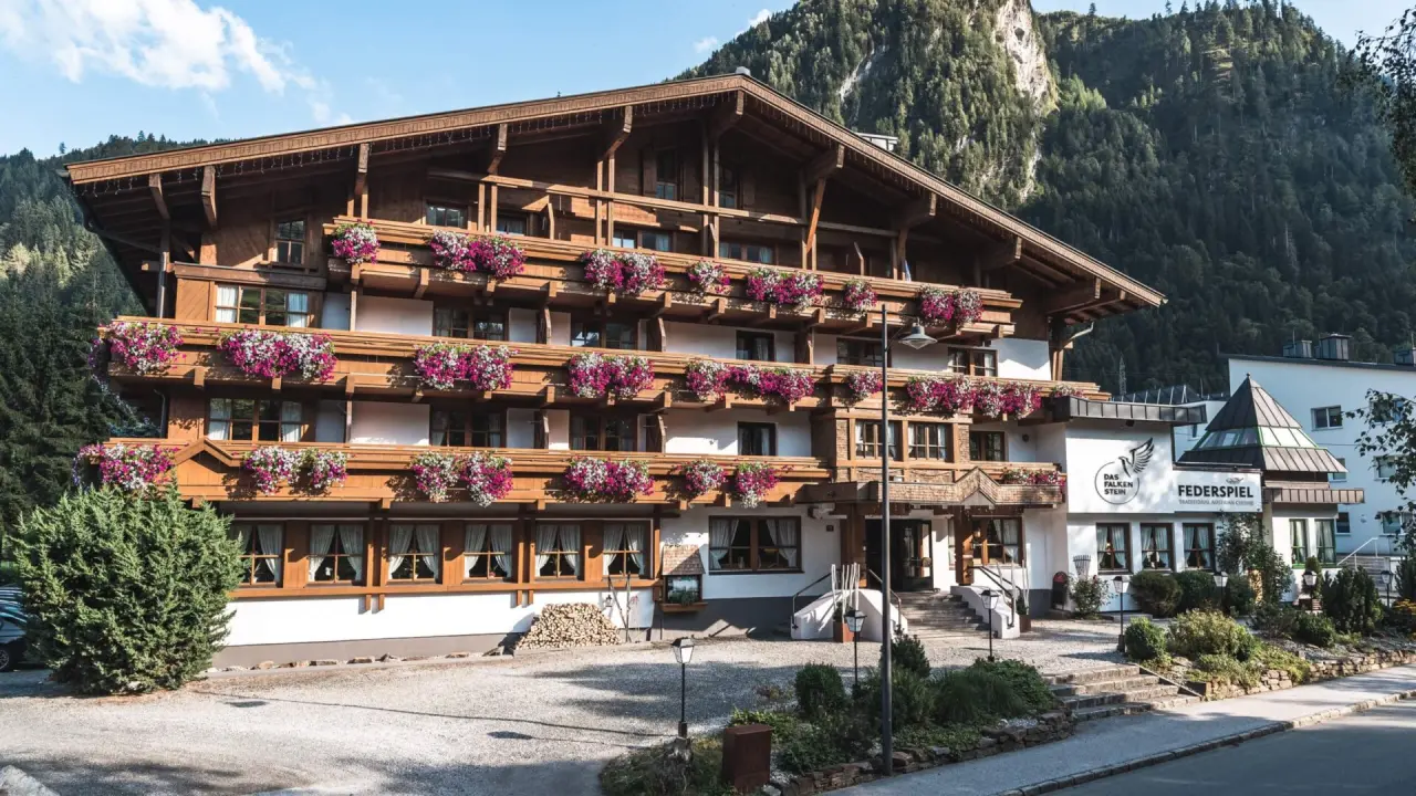 Traditionelles Alpenhotel Das Falkenstein Kaprun mit blumengeschmückten Balkonen und Bergkulisse in Kaprun.