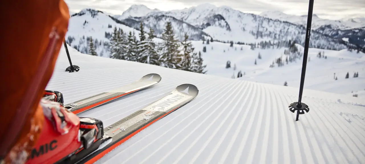 Blick auf frisch präparierte Skipiste und verschneite Berge in St. Johann, Salzburg, ideal für Gäste des Hotel Berghof.