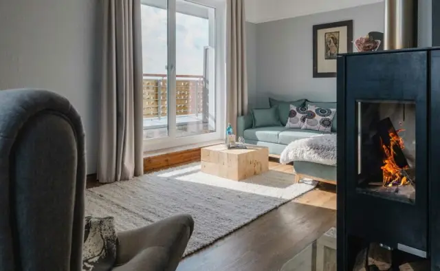 Gemütliches Wohnzimmer einer Suite im Resort Mark Brandenburg mit Kamin, Sofa und Balkon.
