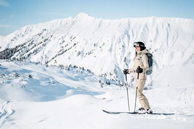 Skifahrer im Tiefschnee vor verschneiten Berggipfeln am Arlberg, Winterurlaub im Sporthotel Steffisalp.
