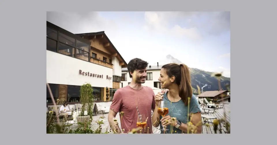 Paar genießt Aperol Spritz auf der Restaurant-Terrasse des Sporthotel Steffisalp mit Bergblick.
