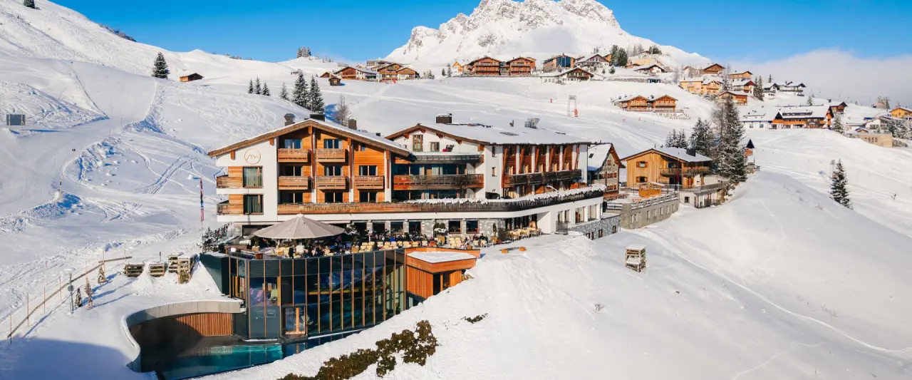 Panoramablick auf das Hotel Goldener Berg, ein luxuriöses Bergresort im Winter mit verschneiten Skipisten und Aussenpool.