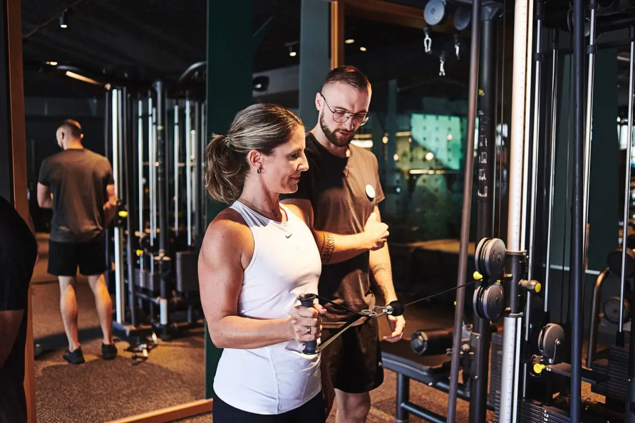 Gäste trainieren im modernen Fitnessbereich des Hotel Zugbrücke Grenzau mit Personal Trainer.