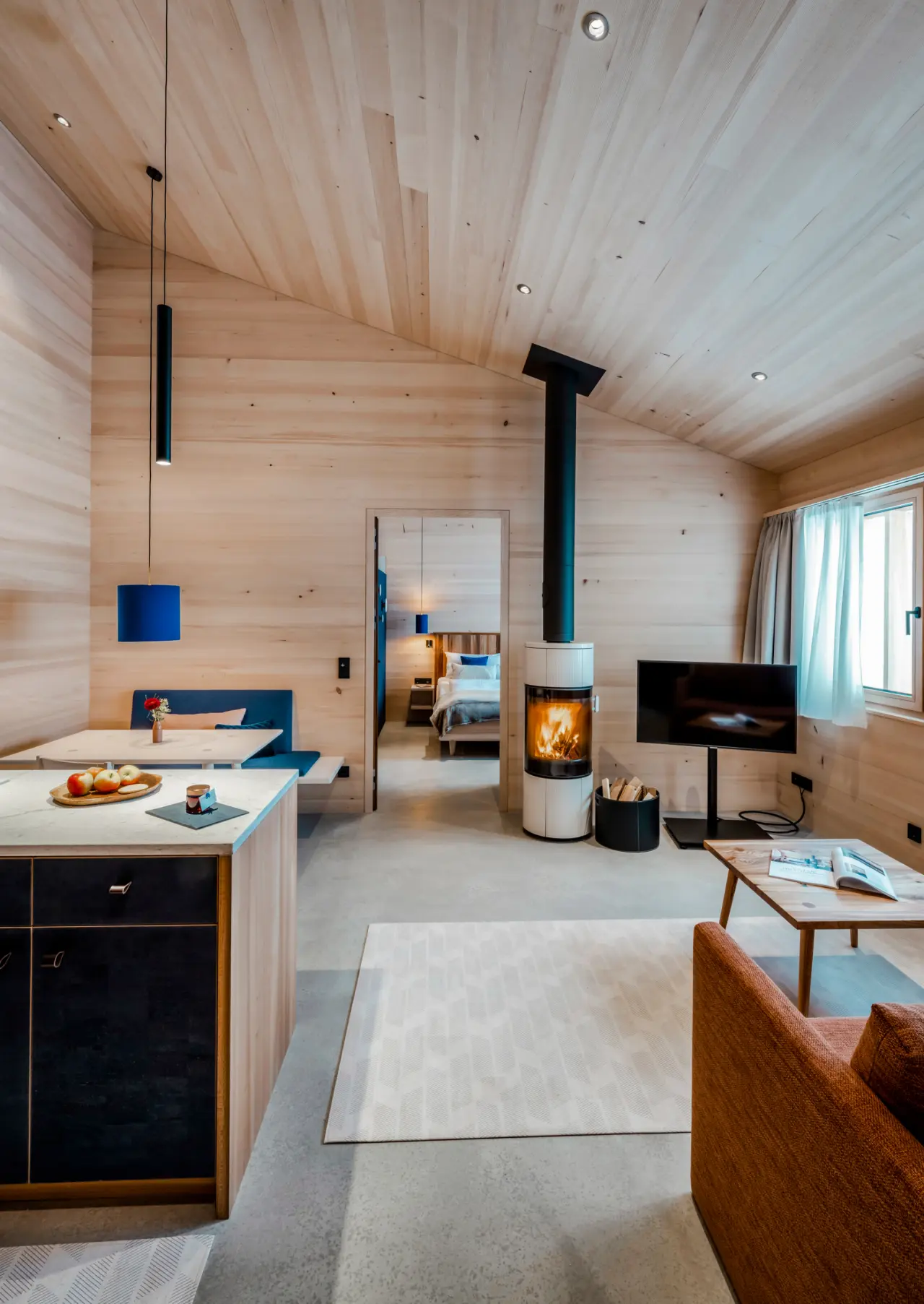 Gemütliches Wohnzimmer einer Suite mit Kamin und Holzwänden in der Fuchsegg Eco Lodge. Blick ins Schlafzimmer.