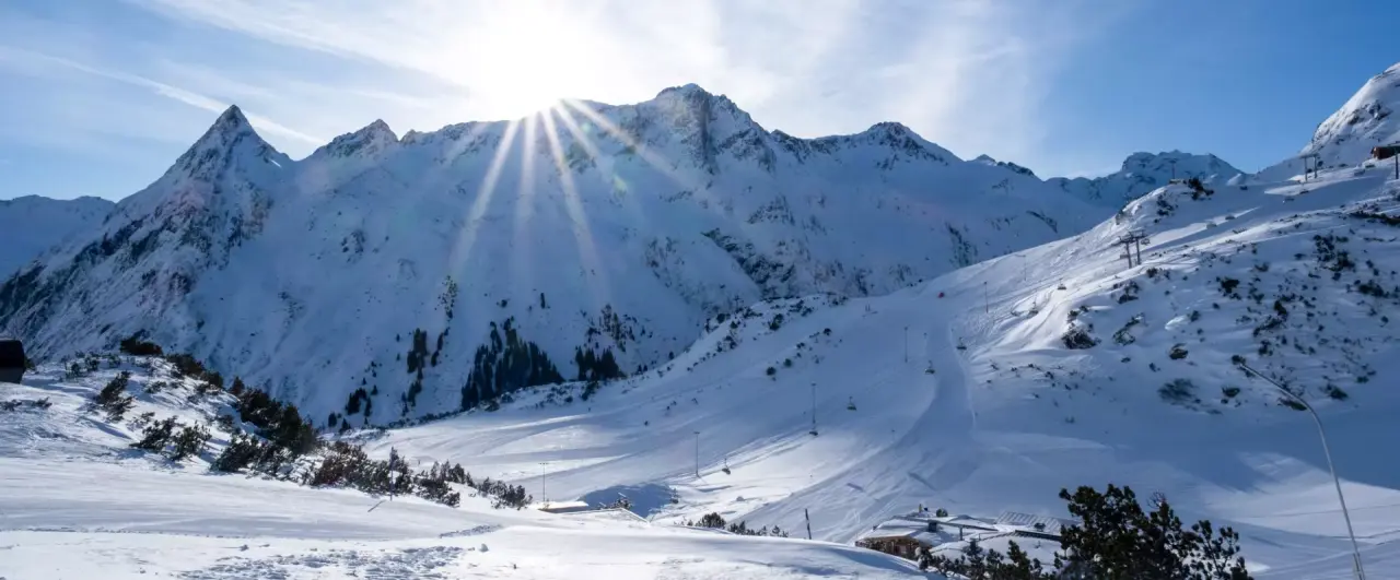 Sonniges Bergpanorama mit verschneiten Skipisten und Skiliften in Ischgl, nahe dem Alpenromantik Hotel Wirlerhof.