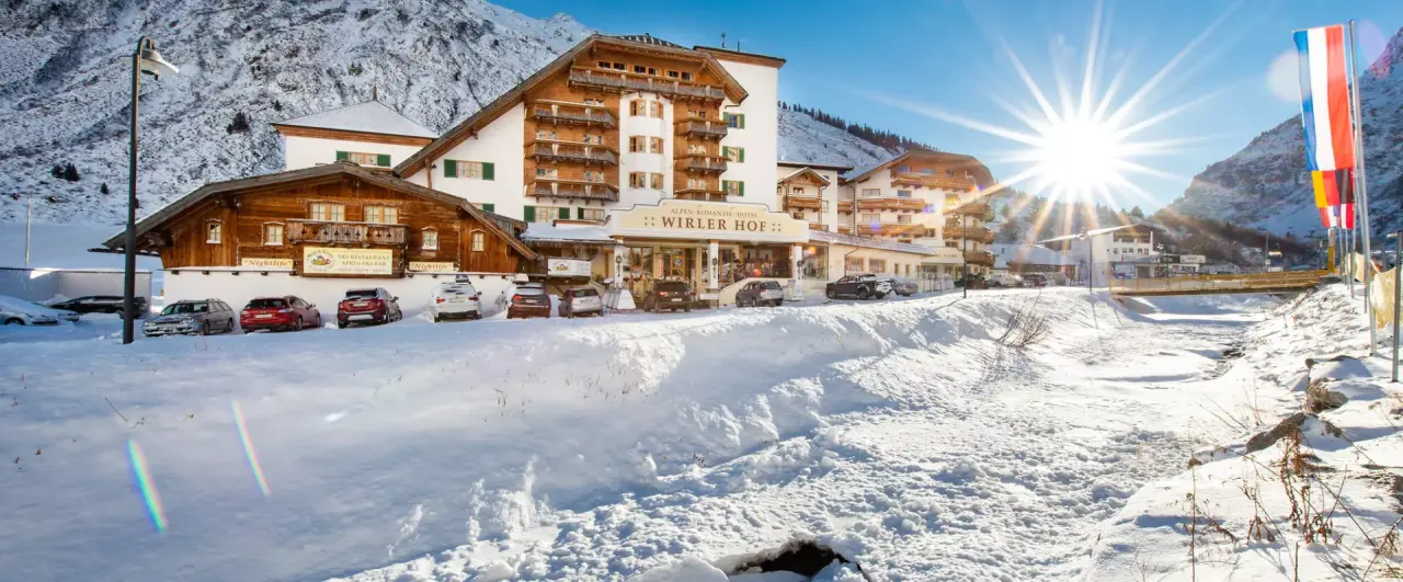 Alpenromantik Hotel Wirlerhof im Winter mit verschneiter Berglandschaft und strahlendem Sonnenschein.