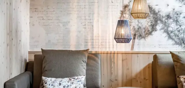 Gemütliche Sitzecke mit Holzwänden, Backstein-Akzent und modernen Hängelampen im Alpenromantik Hotel Wirlerhof.