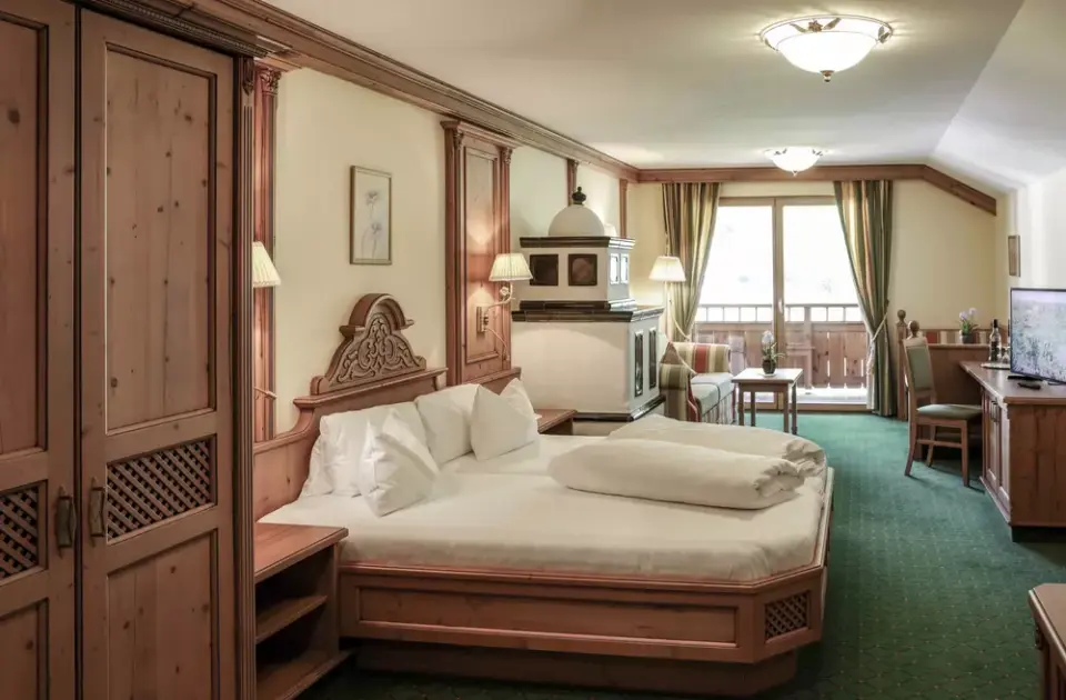 Gemütliches Doppelzimmer im Alpenromantik Hotel Wirlerhof mit traditionellem Holzdesign, Kachelofen und Balkon.