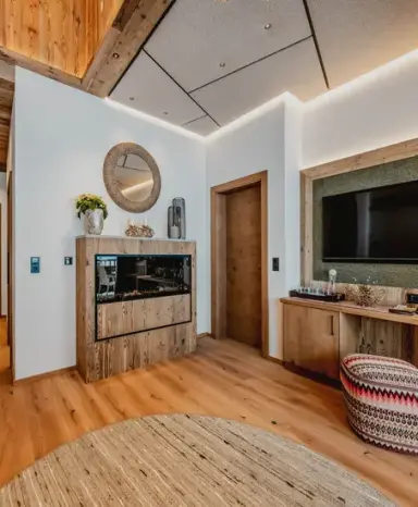 Stilvoller Wohnbereich mit modernem Kamin und TV in einer Suite des Alpenromantik Hotel Wirlerhof.