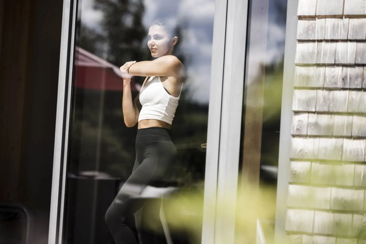 Junge Frau beim Stretching am Fenster im Parkhotel am Soier See. Fitness und Entspannung im Wellnessurlaub.