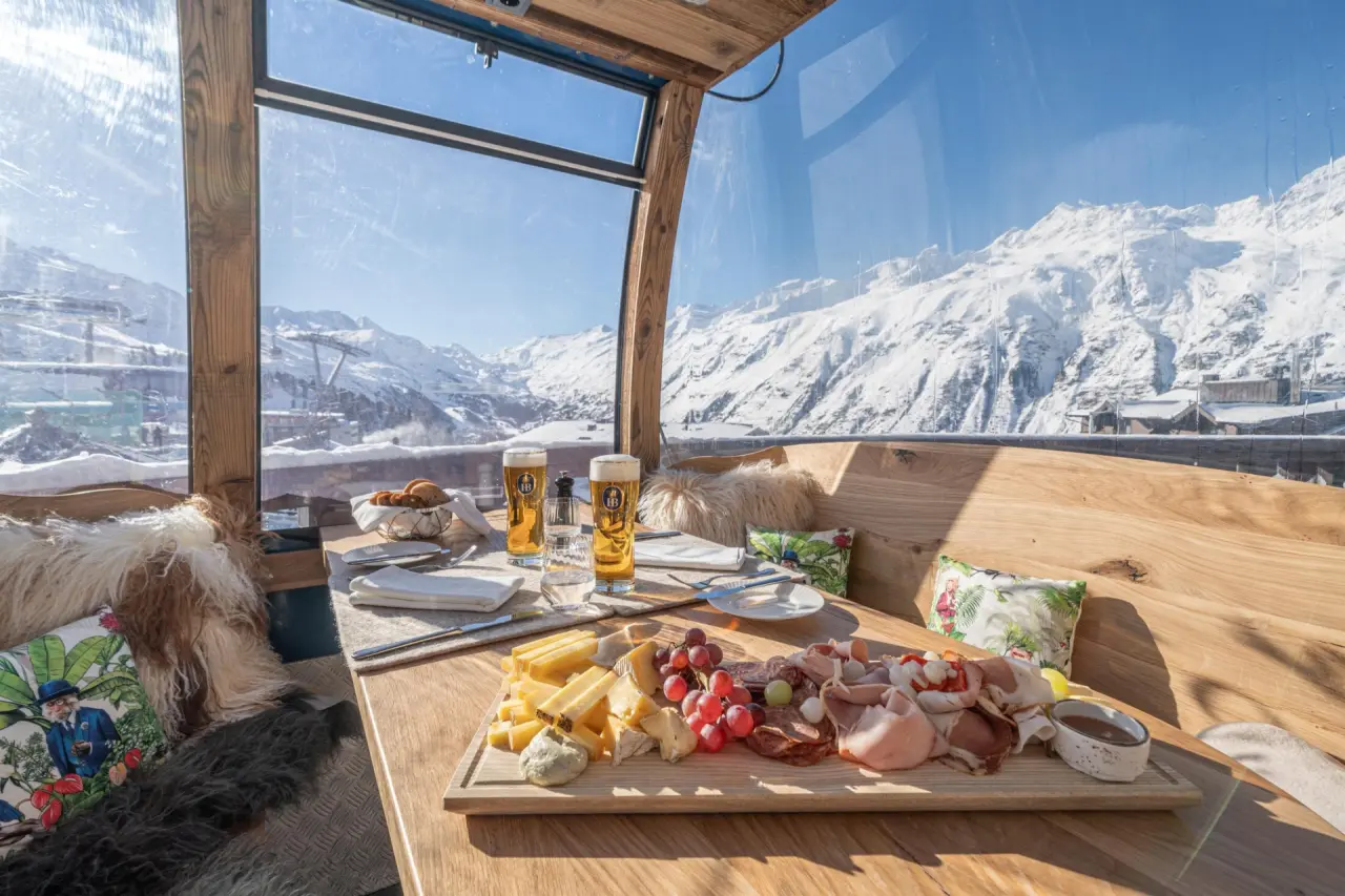 Gemütliches Restaurant mit regionaler Brotzeit und Bier, Panoramablick auf die verschneiten Alpen im Top Hotel Hochgurgl.