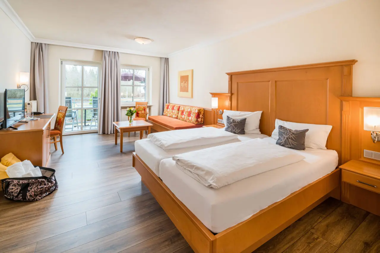 Gemütliches Doppelzimmer mit Holzbett, Sofa und Balkon im Hotel Hammerhof. Komfortabler Rückzugsort für Ihren Aufenthalt.