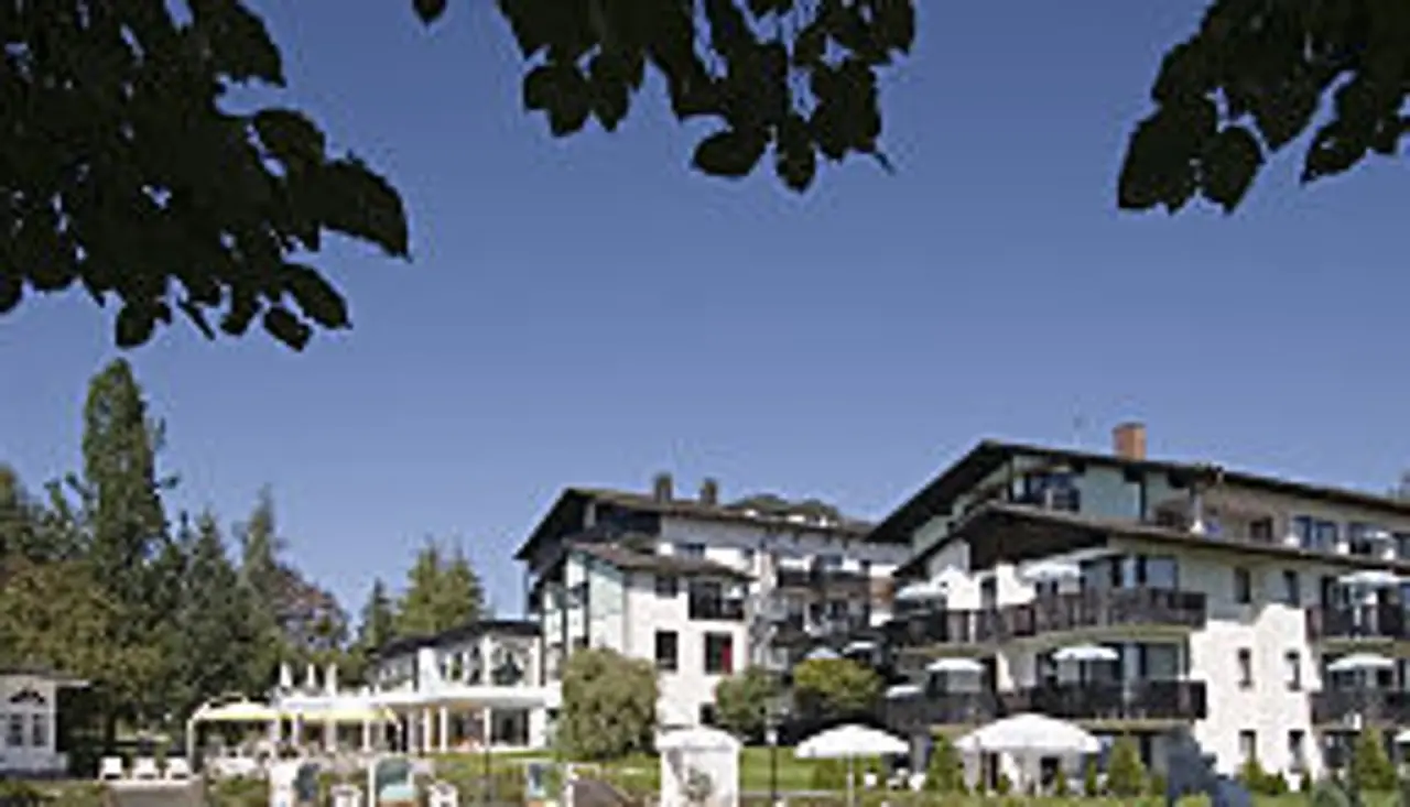 Aussenansicht des Hotel Tanneck Golf & Spa mit mehreren Gebäuden, Balkonen und Sonnenterrasse unter blauem Himmel.