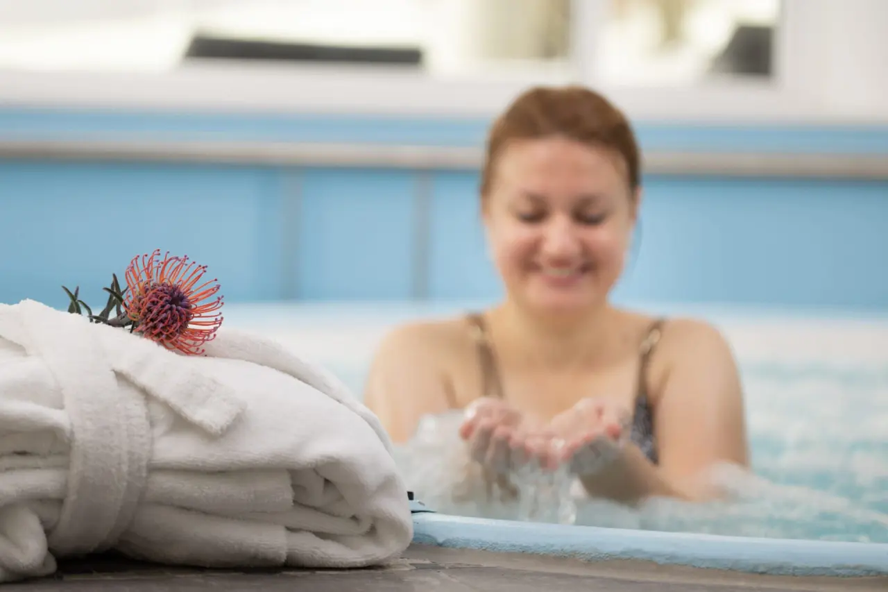 Bademantel und exotische Blume am Whirlpool im Wellnessbereich des Tanneck Golf & Spa Hotels.