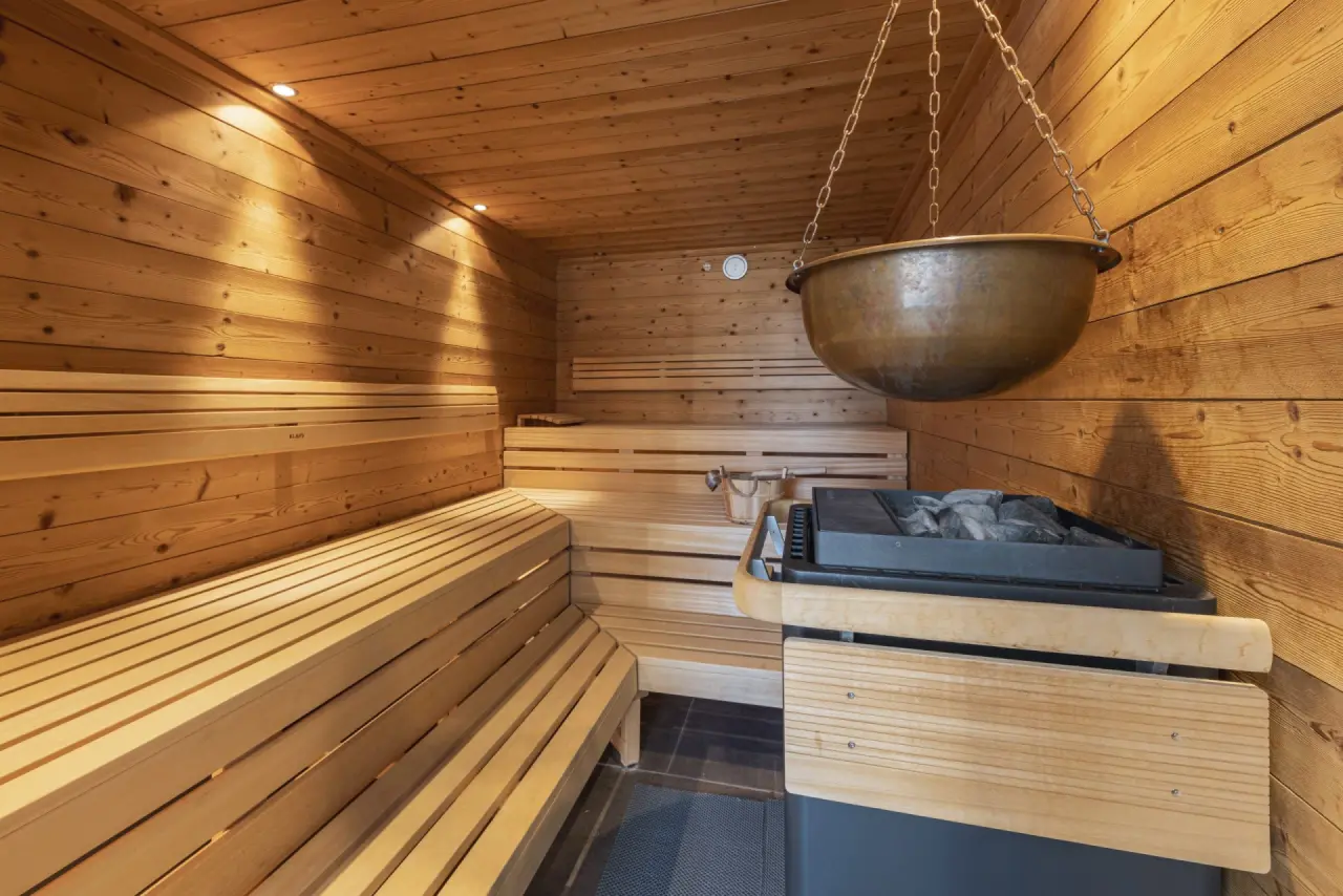 Traditionelle Holzsauna mit Aufgusskessel und Saunaofen im Wellnessbereich des Tanneck Golf & Spa Hotels.