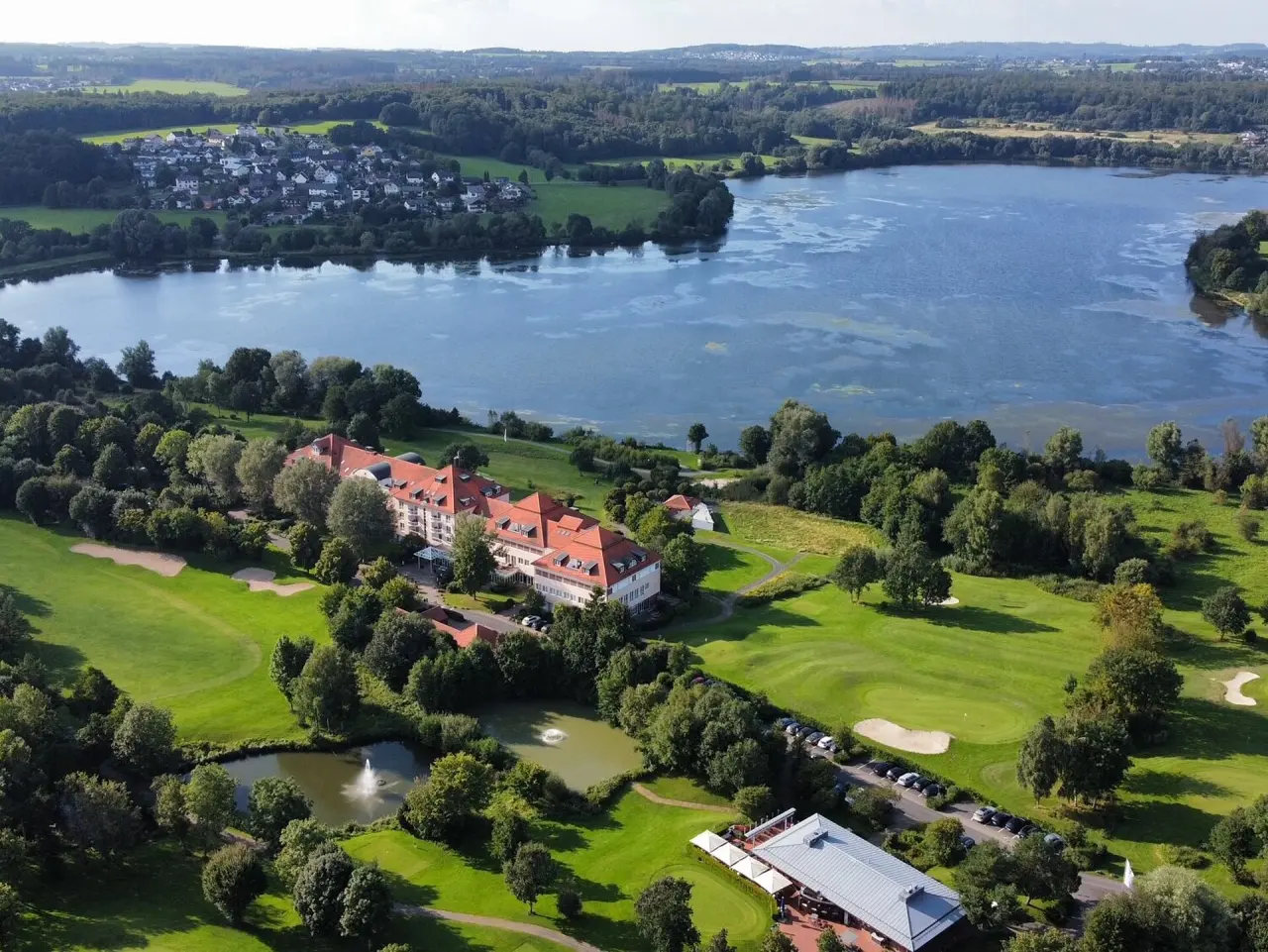Luftaufnahme des Lindner Hotel & Sporting Club Wiesensee mit Hotelgebäude, Golfplatz und dem Wiesensee im Westerwald.