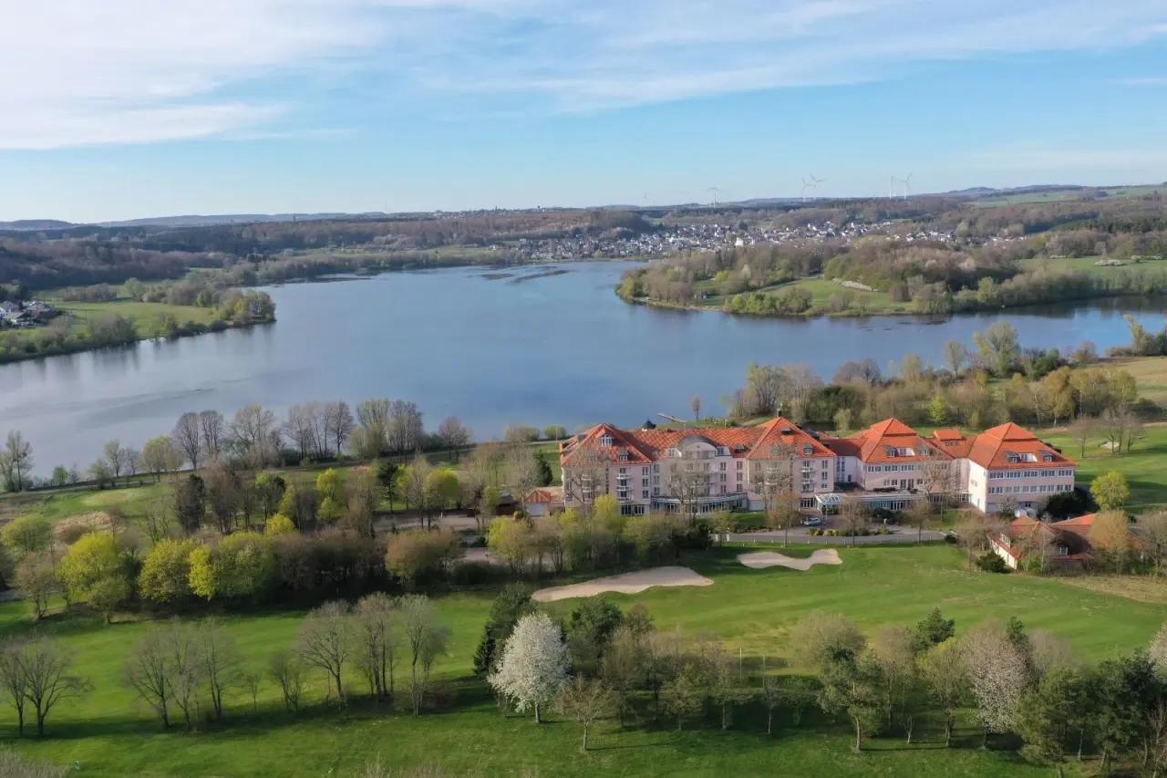 Luftaufnahme des Lindner Hotel & Sporting Club Wiesensee am Seeufer mit Golfplatz und grüner Landschaft.
