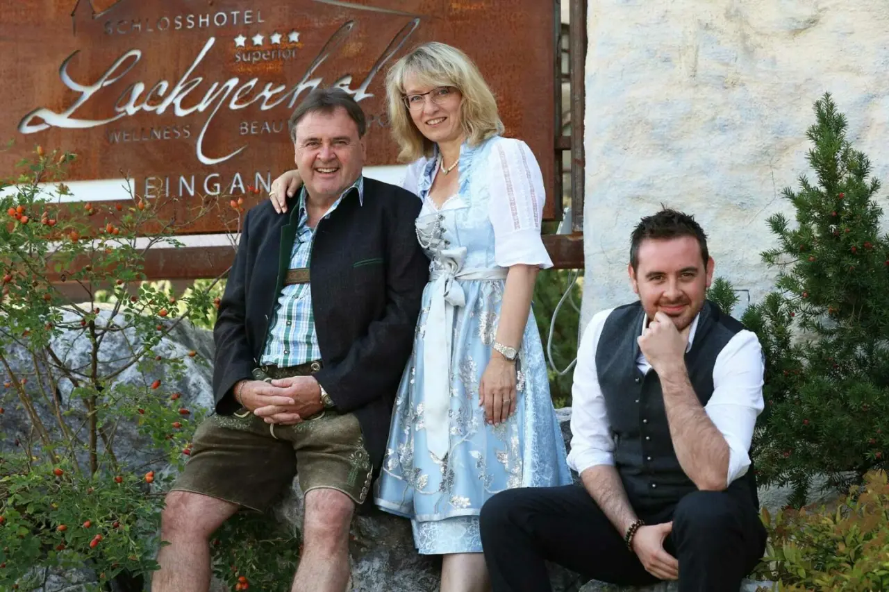 Familienporträt der Gastgeber des Schlosshotel Lacknerhof****S am Eingang mit Wellness-Schriftzug.