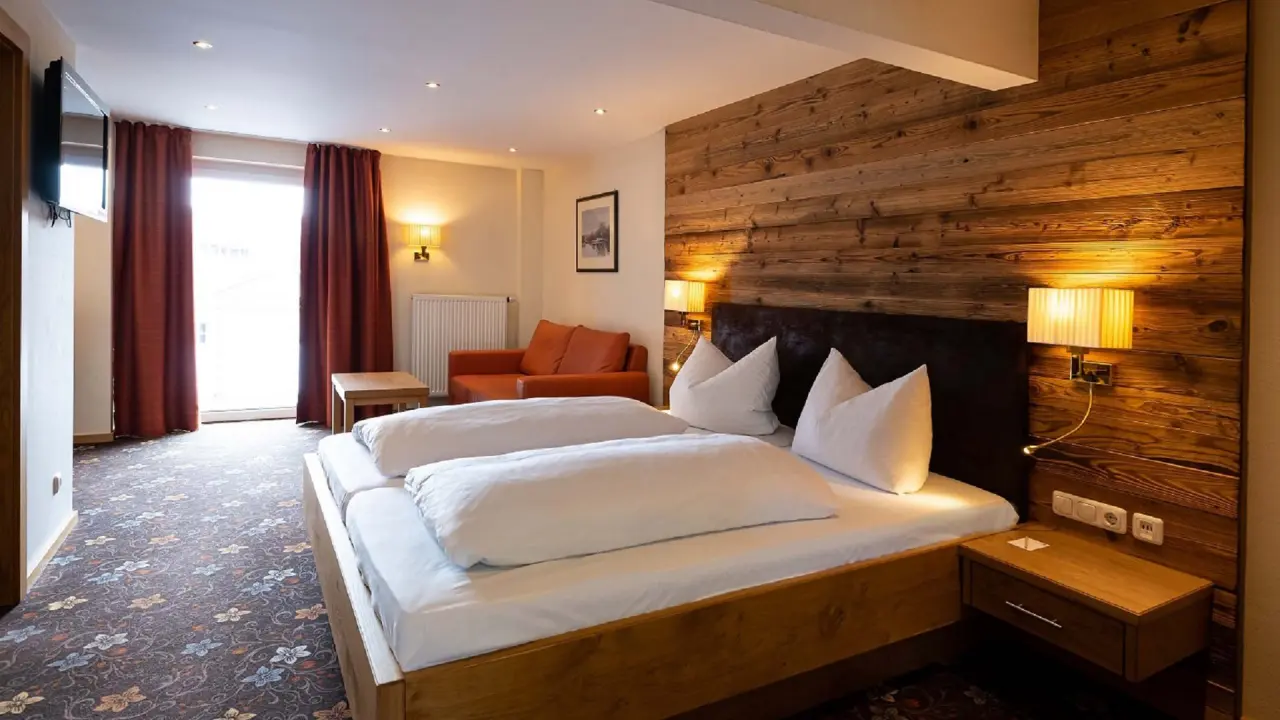 Gemütliches Doppelzimmer mit Holzwand, Sofa und Balkon im Wellnesshotel Randsbergerhof