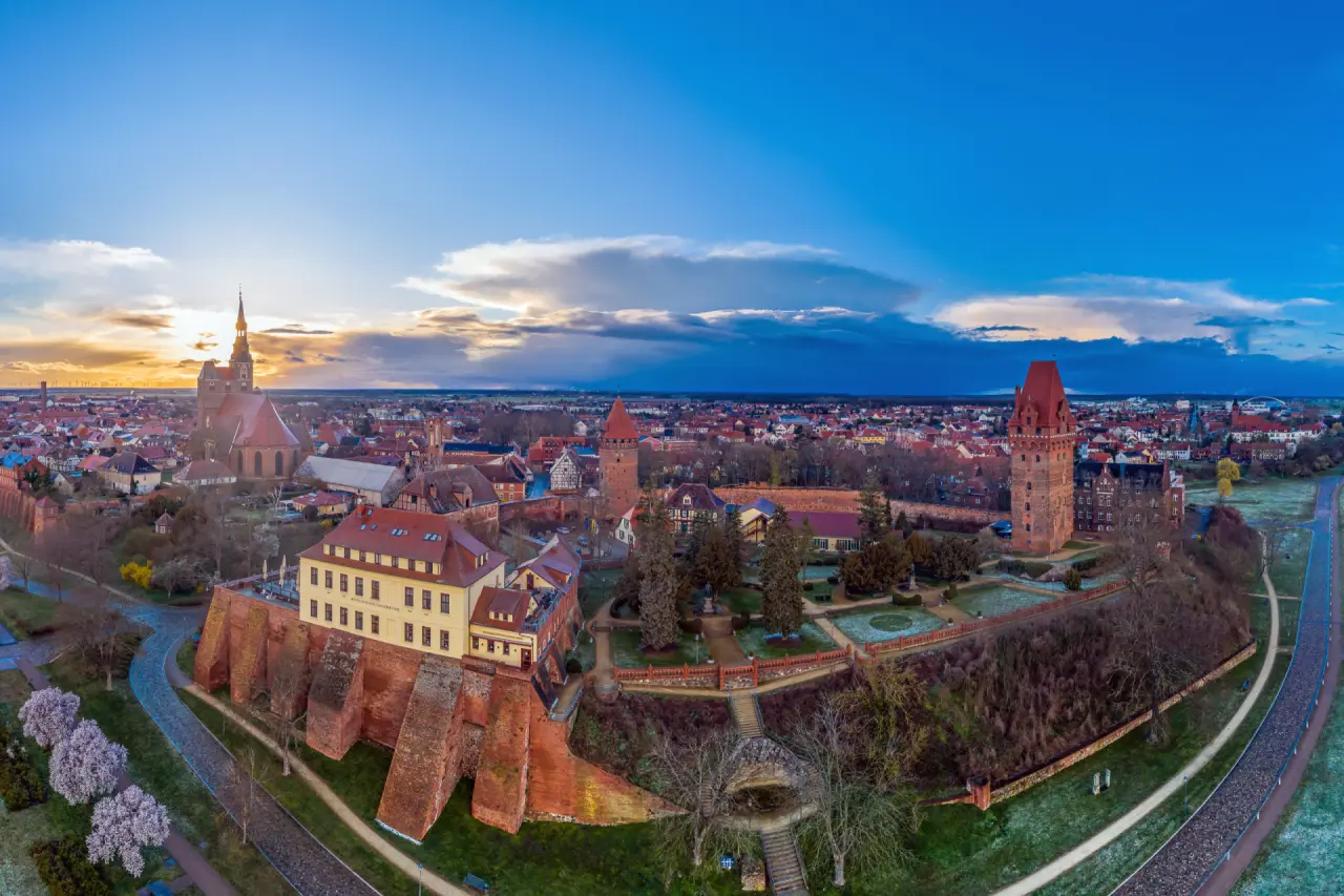 Panoramablick auf das historische Hotel Schloss Tangermünde und die Altstadt bei Sonnenuntergang mit Burg und Stadtmauer.