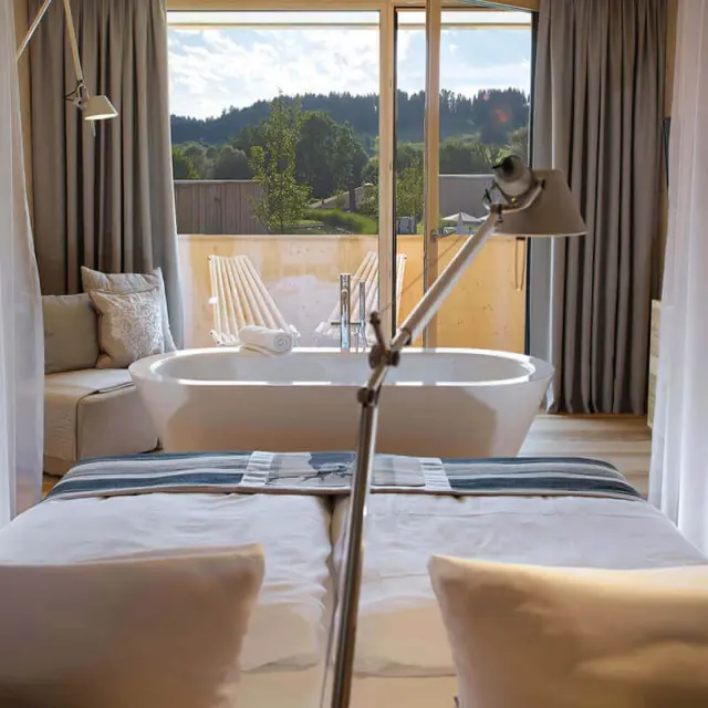 Luxuriöses Hotelzimmer im Tannenhof Sport & SPA mit freistehender Badewanne und Panoramablick auf die Natur.