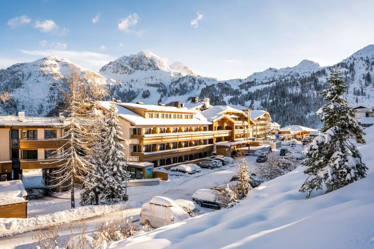 Winterliche Aussenansicht des Hotel Gartnerkofel mit verschneiten Bergen und Tannen im Nassfeld.