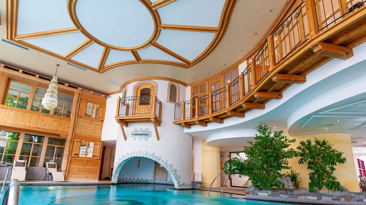 Grosszügiger Innenpool mit alpiner Holzarchitektur und Tageslicht im Wellnesshotel Warther Hof.