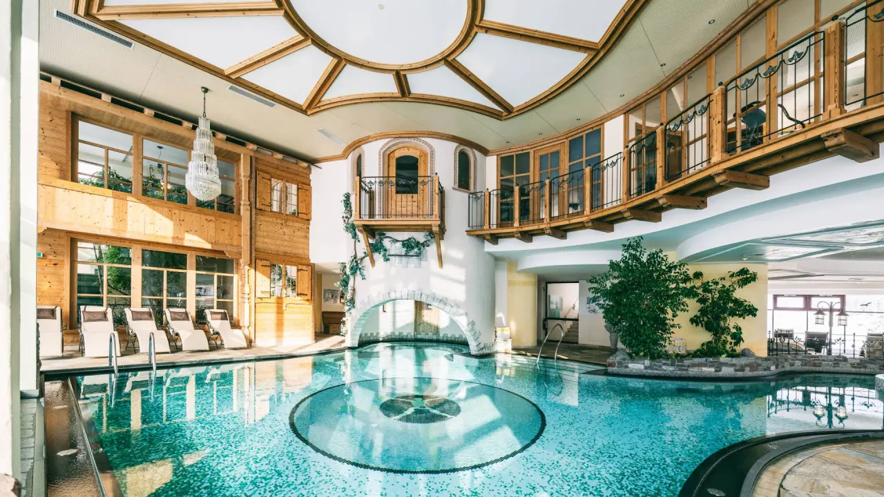 Grosszügiger Innenpool im Wellnesshotel Warther Hof mit alpiner Holzarchitektur, Tageslicht und bequemen Liegestühlen.