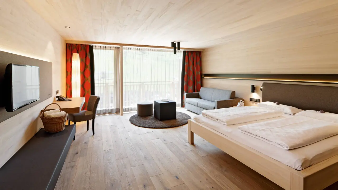 Modernes Doppelzimmer mit Holzelementen, Balkon und Bergblick im Wellnesshotel Warther Hof.