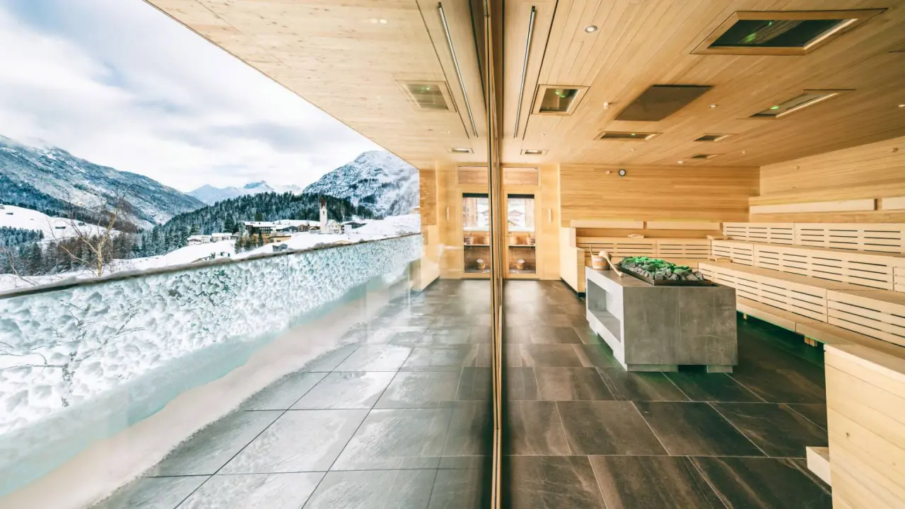 Panoramasauna mit Bergblick im Wellnesshotel Warther Hof. Moderne Holzsauna mit Blick auf verschneite Alpenlandschaft.