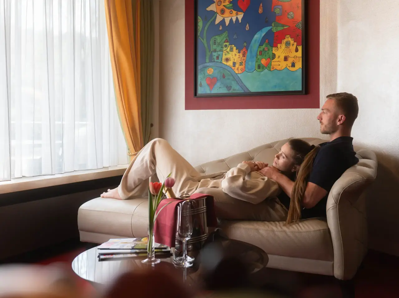 Paar entspannt auf Sofa im komfortablen Hotelzimmer des Golf- & Alpin Wellness Resort Hotel Ludwig Royal.