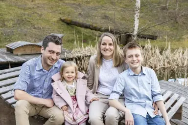 Lachende Familie auf einer Holzbank am Teich im Aussenbereich des Hotel Käppelehof