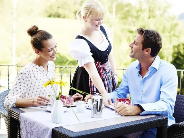 Gäste genießen Kaffee und Kuchen auf der Sonnenterrasse des Hotel Käppelehof, serviert von freundlichem Personal.
