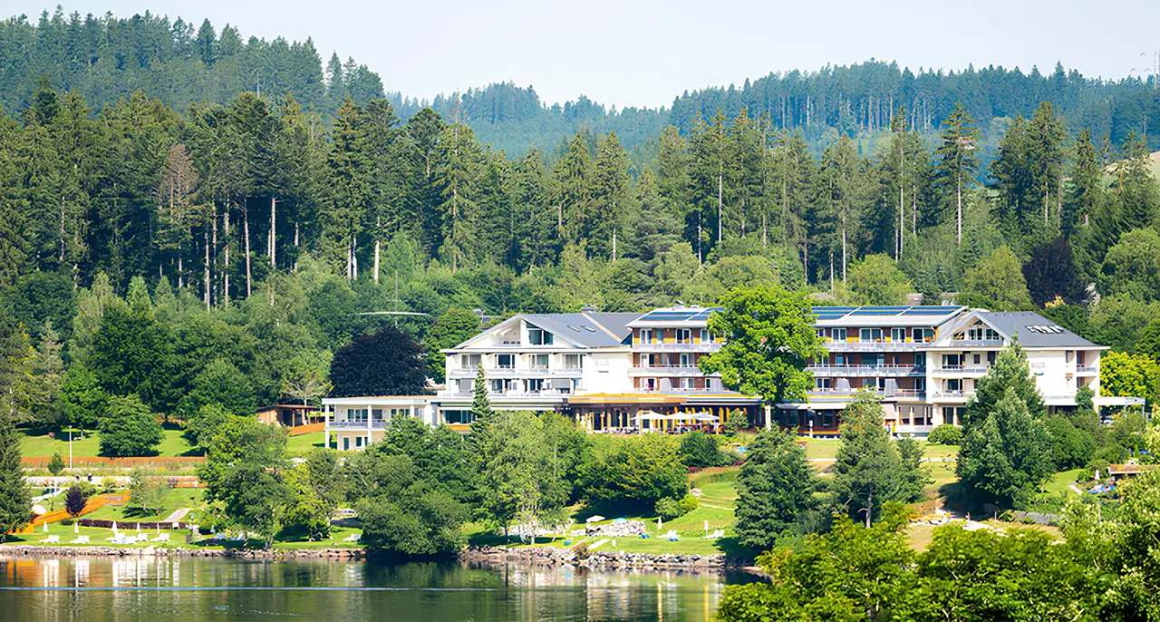 Brugger's Hotelpark am Titisee mit Blick auf den See und die umliegenden Wälder. Idyllische Lage für Wellness und Erholung.