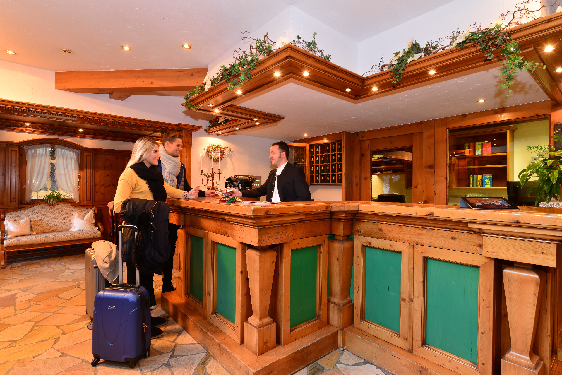 Hotel Alpenstüble in Mittelberg – Freundlicher Empfangsbereich mit Gästen beim Check-in | Wellnesshotel Alpen