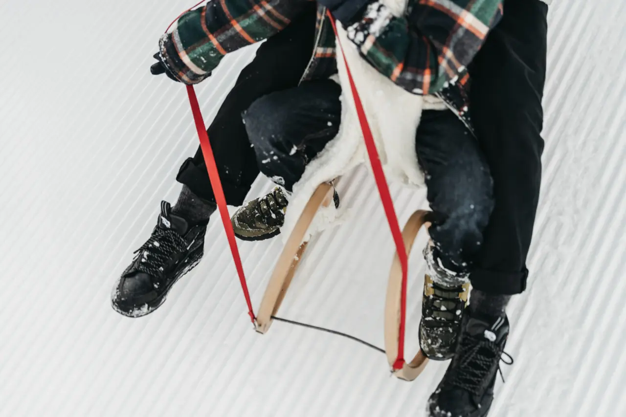 Winterliche Aktivität: Zwei Personen auf einem Holzschlitten im frisch präparierten Schnee, ideal für Gäste des Hotel Oberforsthof.