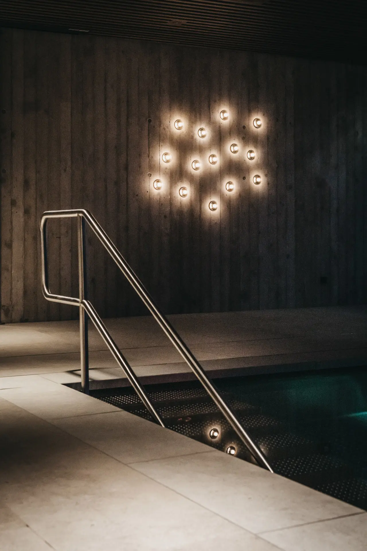 Modern gestalteter Innenpool mit indirekter Beleuchtung und Betonwand im Spa-Bereich des Hotel Oberforsthof.