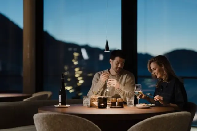 Romantisches Abendessen für zwei im stilvollen Restaurant des Hotel Oberforsthof mit Panoramablick auf die Berge bei Nacht.