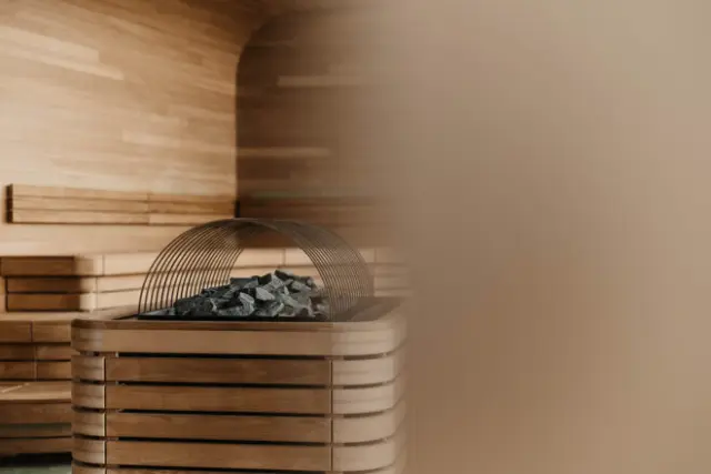 Moderner Saunaofen mit Saunasteinen in der Holzsauna des Hotel Oberforsthof für entspannende Wellnessmomente.